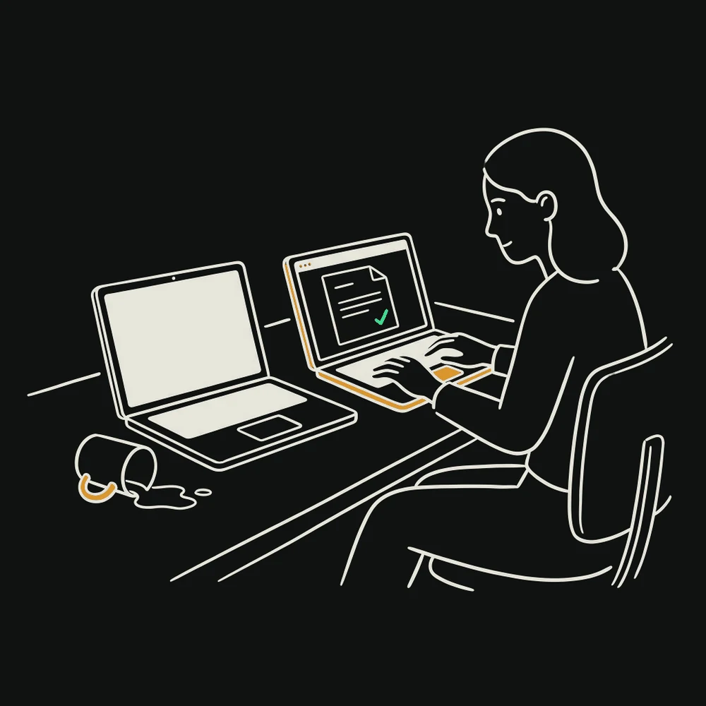 A laptop with a blank screen and a knocked-over mug beside it, while the woman who was using it works on a second laptop showing the same document.